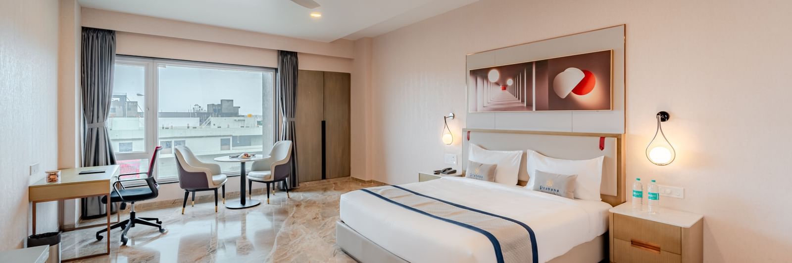 Spacious hotel room featuring a king-size bed, work desk, and city views | Premium Room | Pravasa Hotel, Vijayapura