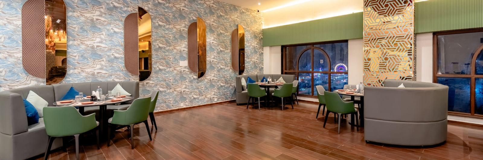 The hotel dining area with green booths and bright orange chairs | Pravasa Hotel, Vijayapura