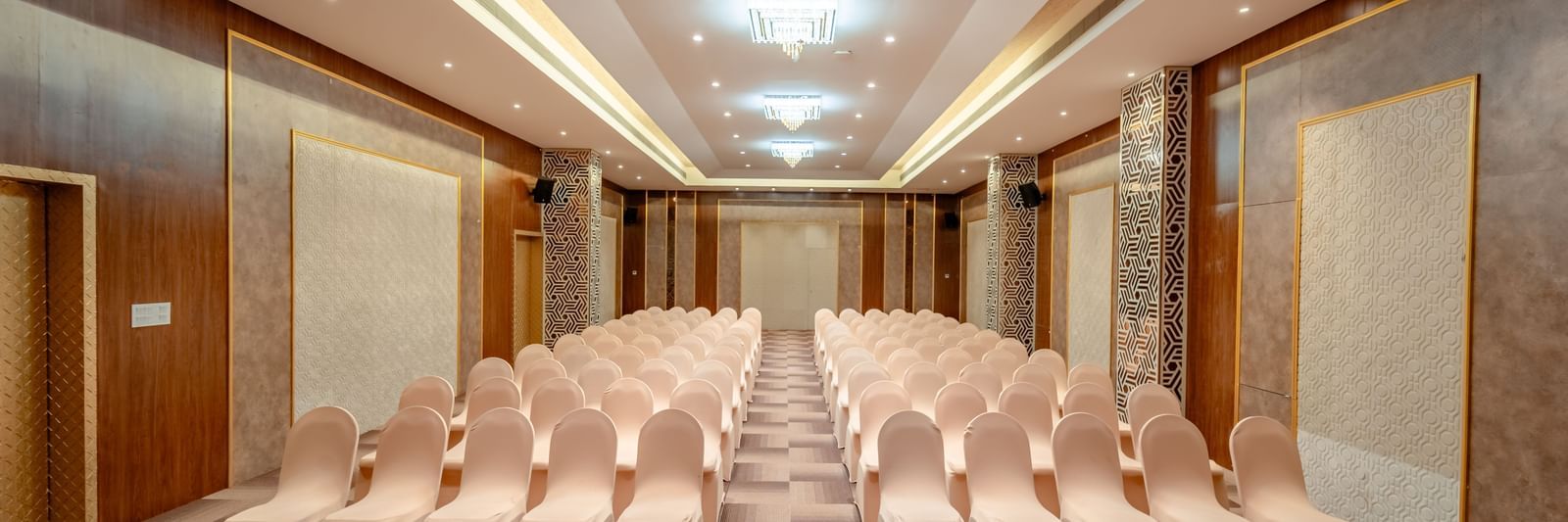A ballroom set up with rows of beige chairs for a presentation or conference | Meetings & Events | Pravasa Hotel, Vijayapura