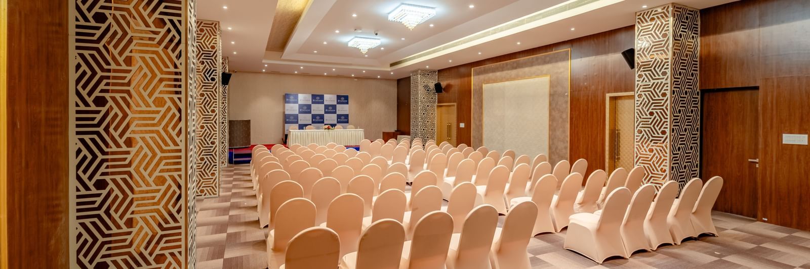 Ballroom set up with rows of beige chairs for a presentation or conference | Meetings & Events | Pravasa Hotel, Vijayapura