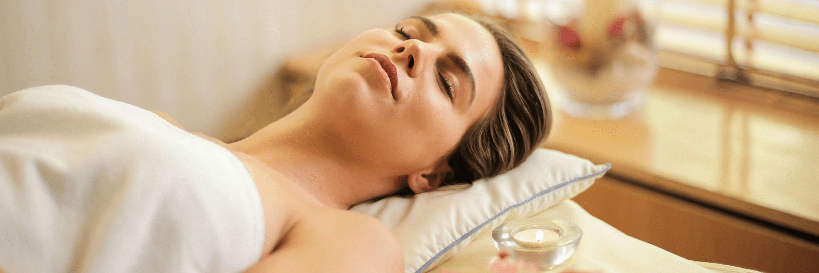 A woman lying down on a bed all relaxed in a brightly lit room.