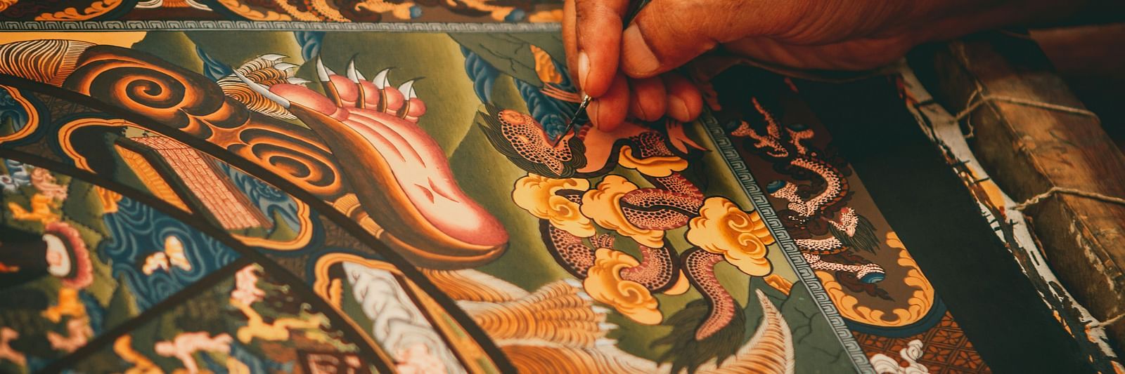 A close up shot of a person hand seen painting a Thangka painting