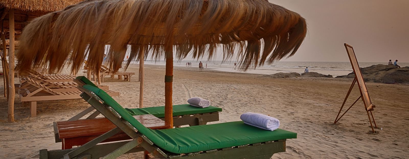 Beach loungers under thatched umbrellas facing the sea at Royale Amata by the Beach Restaurant