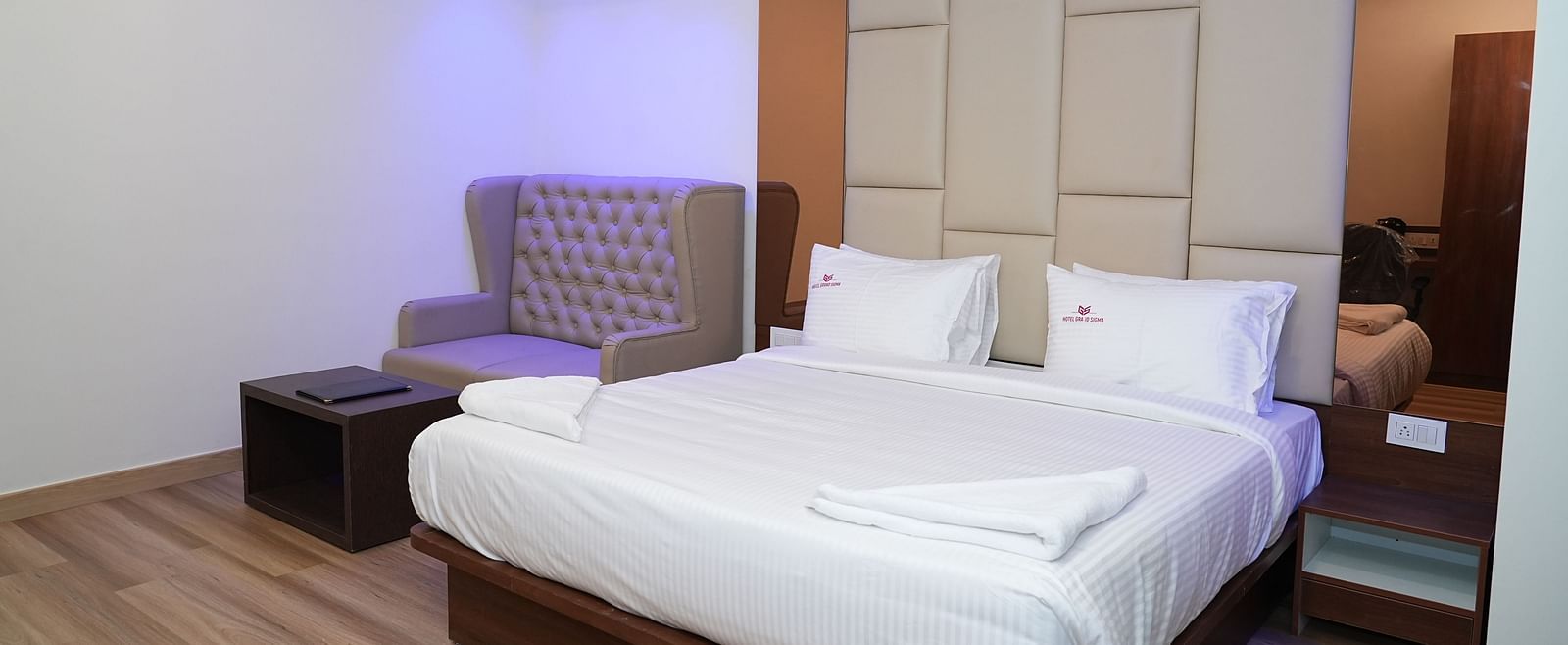 corner view image of the suite with a comfortable double bed along with a cushioned couch at the far end of the room - Hotel Grand Sigma