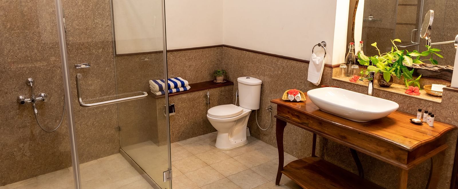 Bathroom with a glass shower, white sink on a wooden stand, and a window - BluSalzz Collection - Tranquil Resort, Wayanad