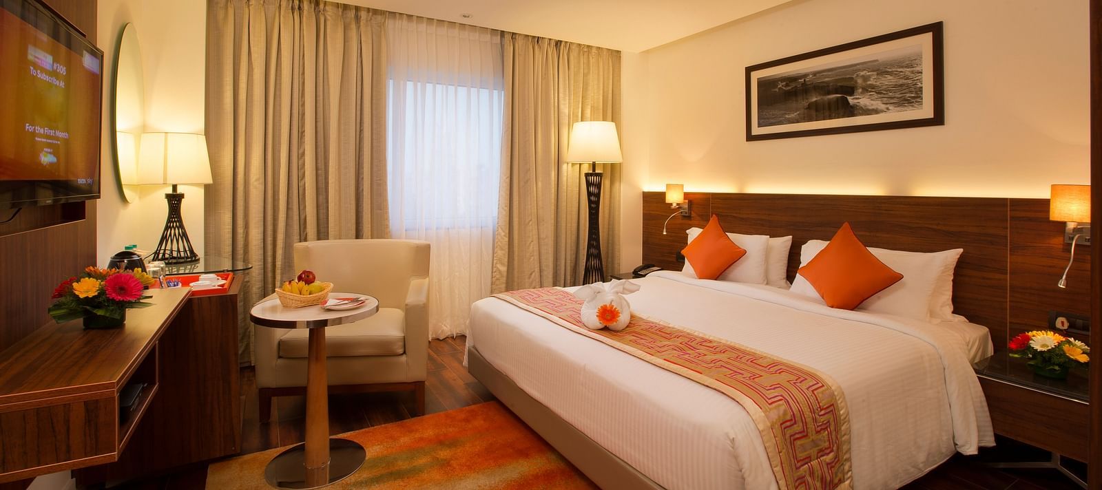 A hotel room featuring a large bed with white and orange linens, a work desk and a black-and-white photo of a landscape on the wall - Hotel Southend by TGI - Bommasandra, Bangalore