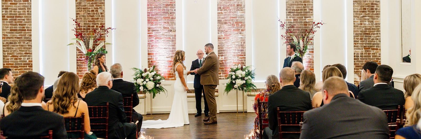 A couple standing, facing each other, in a hall full of people sitting in theater style seating arrangement - The Grand Hotel & Ballroom, McKinney