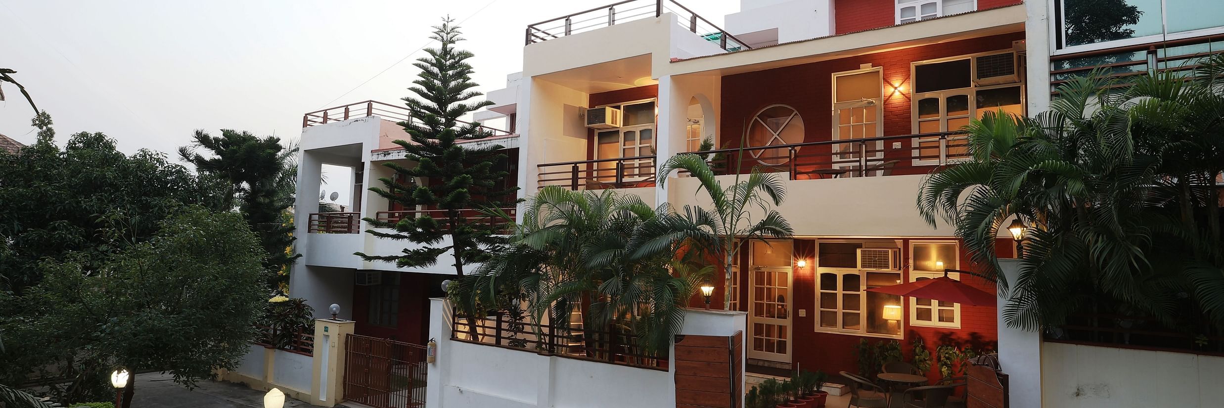 A facade image of a two storey building surrounded by trees and there are also lights beside the pathway to the entrance gate - Lamrin Boutique Cottages Rishikesh