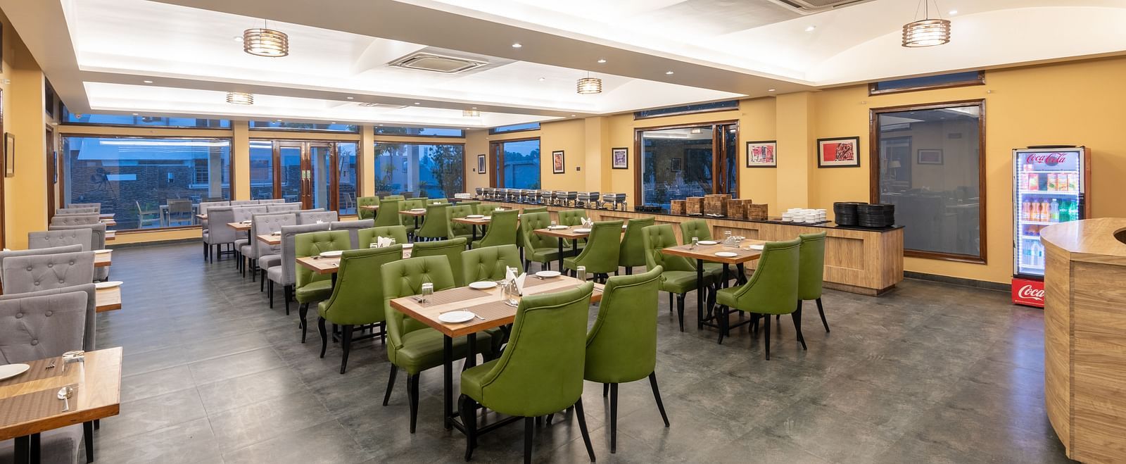 Brightly lit diagonal view of the restaurant at DLS Forest Vines Resort, showcasing tables and seating arranged for guests.
