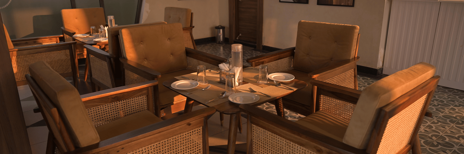 Cosy indoor lounge with wooden chairs arranged around a central table at Hotel Sonar Bangla Mayapur.
