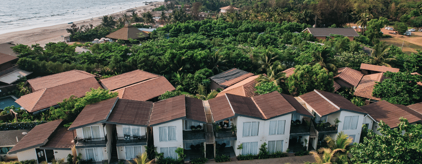 an aerial vie image of the facade of sibaya beach resort, morjim beach that is surrounded by lush tropical greenery