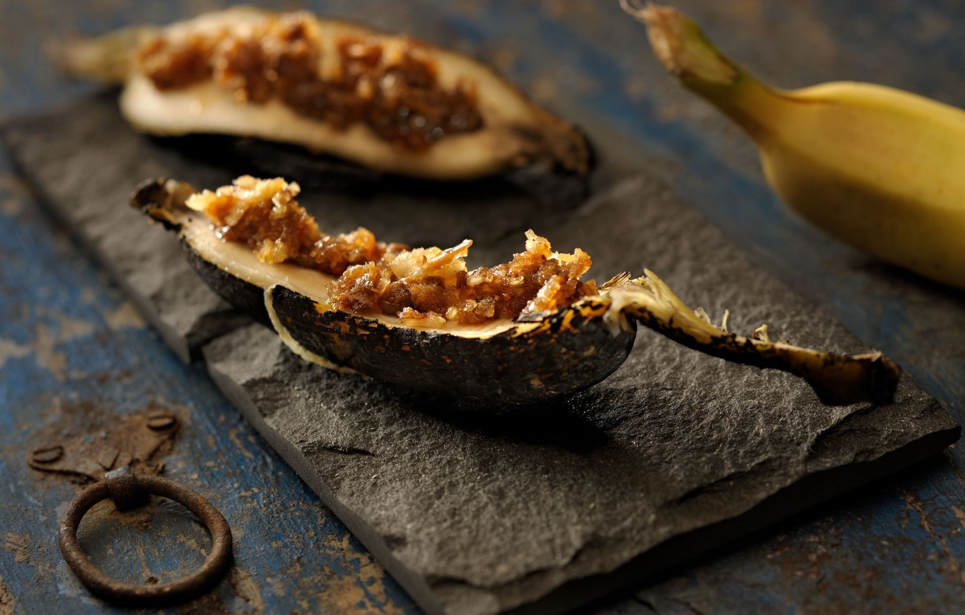 Baked banana with sweet filling on a slate dish.