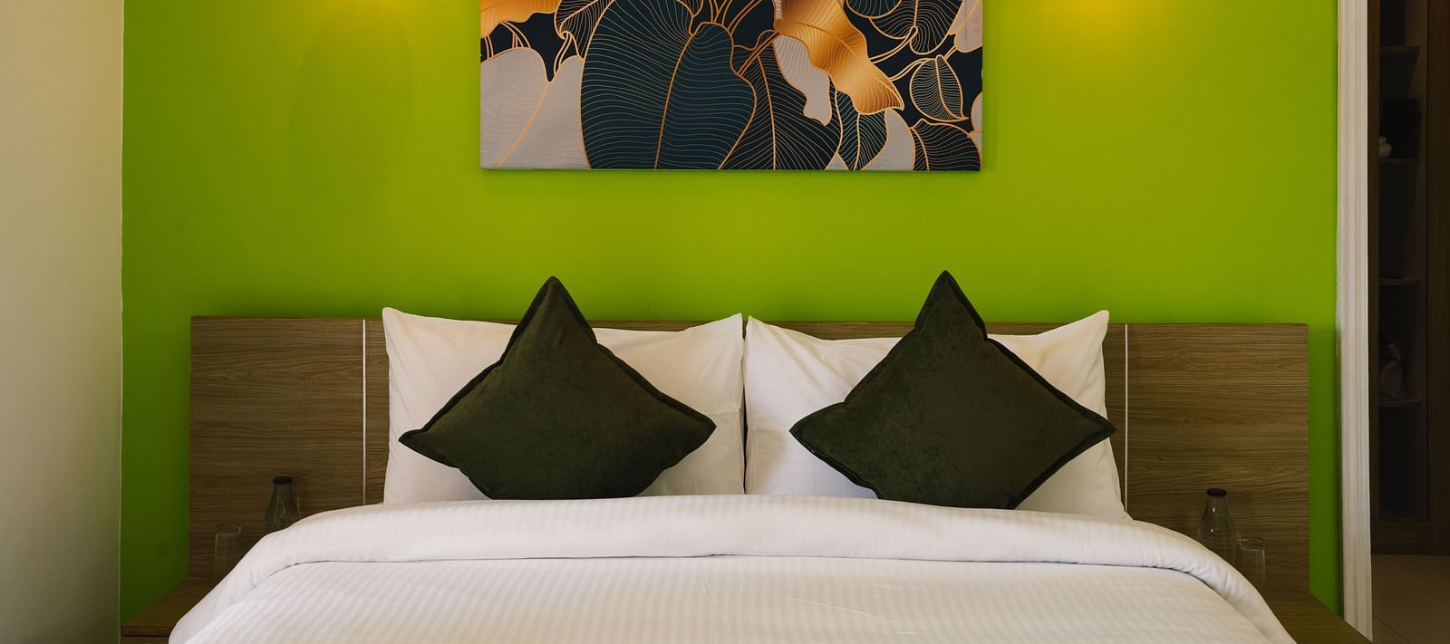 A close-up view of the neatly made bed with a photo frame above the headboard and two light lamps on either side at BluSalzz Villas - The Green Roof, Bhimtal.