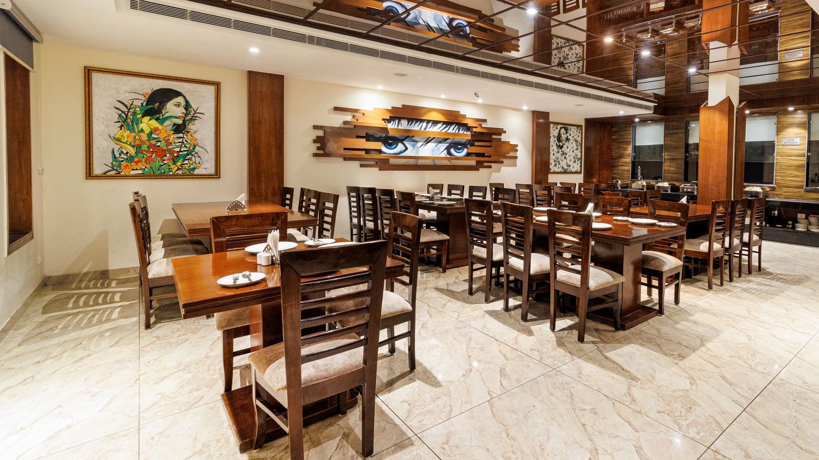Restaurant at Inde Reva Resorts Rishhikesh featuring wooden furniture, open ceiling design, framed art, and tiled flooring.