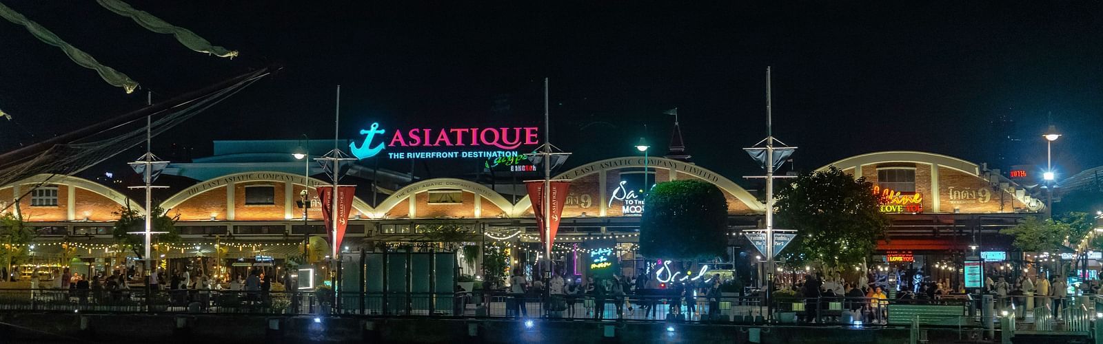Facade view of Asiatique Waterfront with Chao Phraya River in the foreground.