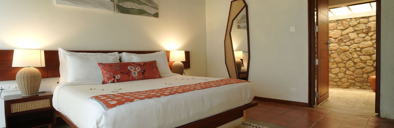  A well-appointed bedroom at Vaasta Vagamon featuring a large bed, bedside tables with lamps, a floor-length mirror, and artwork.