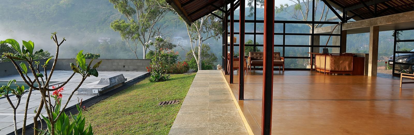  A spacious open-air pavilion at Vaastha Vagamon, featuring an exposed roof structure and offering panoramic views of the surrounding hills.