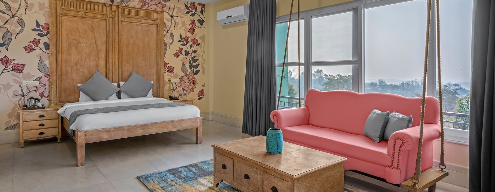 An image featuring a spacious bedroom with a king-size bed, a sofa, and a large window with a view - atman, dharamshala