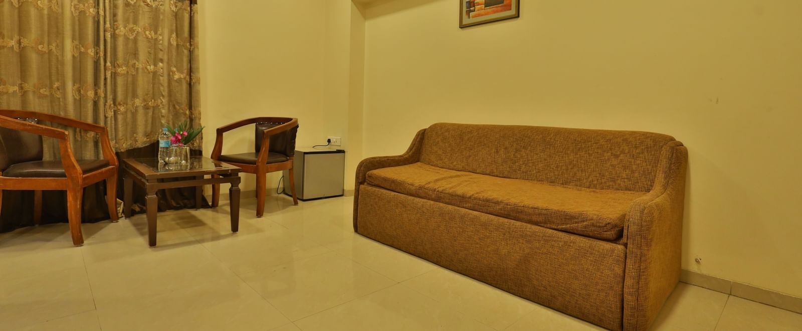 A suite's living room area, furnished with a long sofa, chairs, and a coffee table - Retreat Heritage, Lonavala