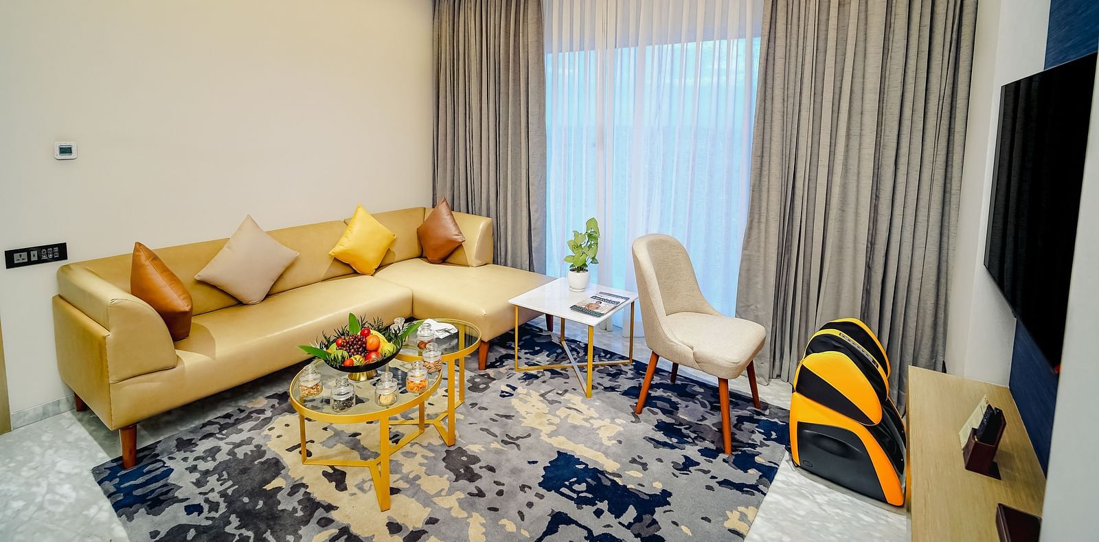 An image of the living room in  Deluxe Room with a large leather couch, a coffee table and a wall-mounted television