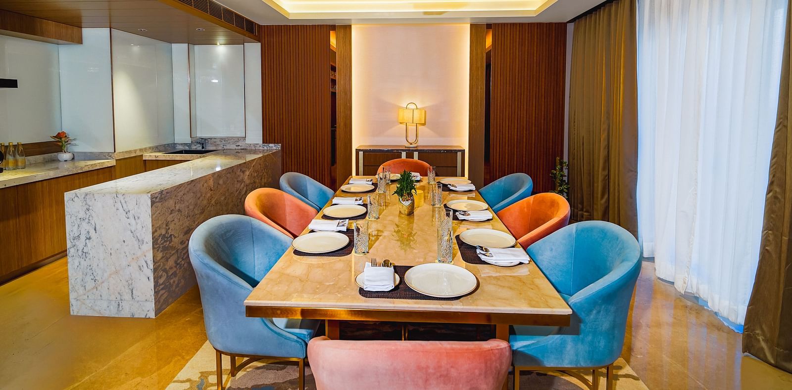 An image of a dining table under an warm and stylish light with upholstered chairs placed around it
