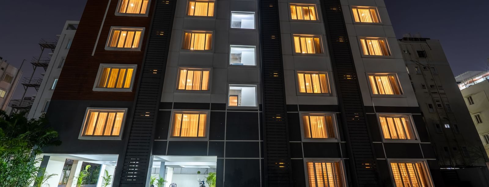 A low-angle shot of the illuminated facade of Destino by Monday Hotels, Gachibowli, at night, featuring its entrance.