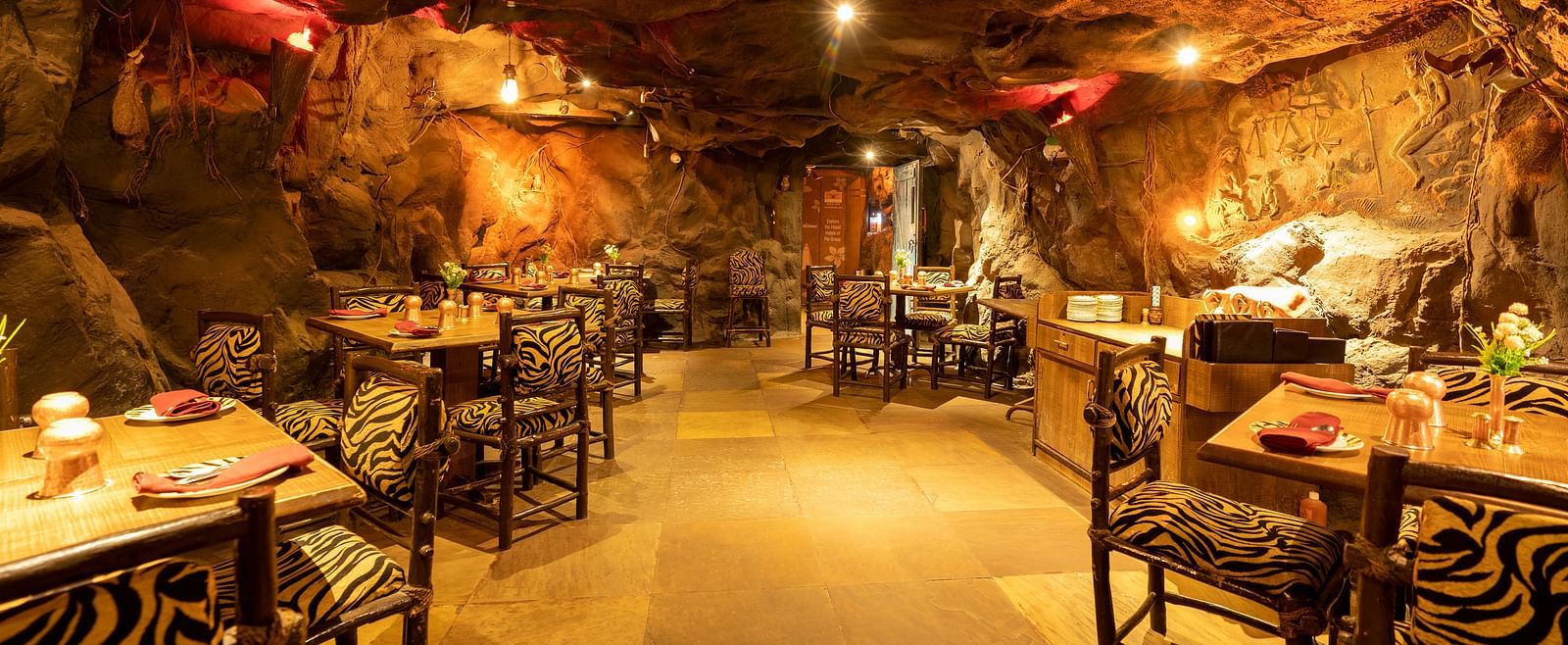 An image of cave themed restaurant with a few sets of chairs and table - Hotel Pai Vista, Mysore
