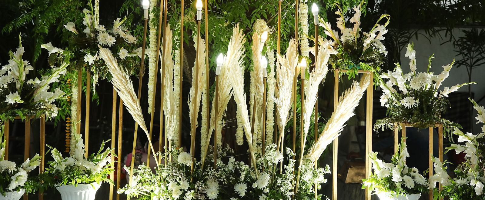 Decorative setup at Tisya Farms, Gurgaon with bamboo sticks, spotlights, and white flowers.