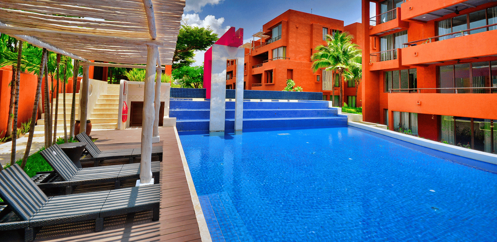 Vibrant hotel facade featuring sun loungers and a pool.