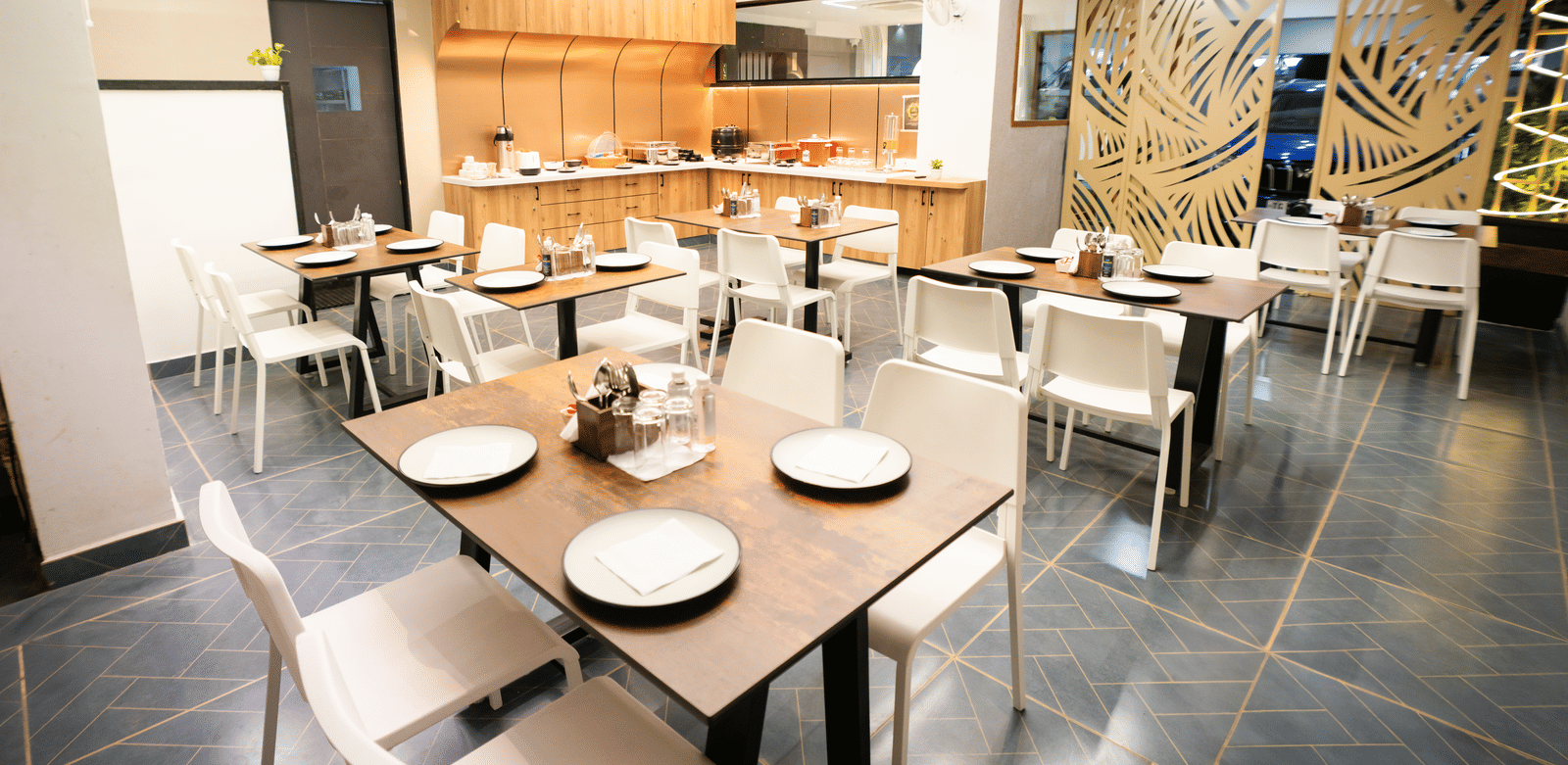 Restaurant seating area with tables and chairs set for dining at Sunrise Business Hotel, Hyderabad.