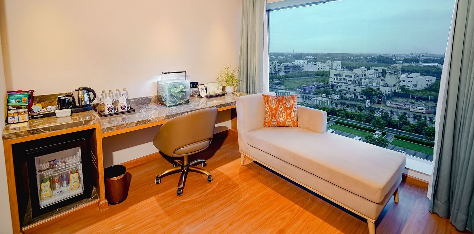 A view of the vibrant city of Madurai seen from our hotel room with a couch and a work desk placed near the window from which the view is seen