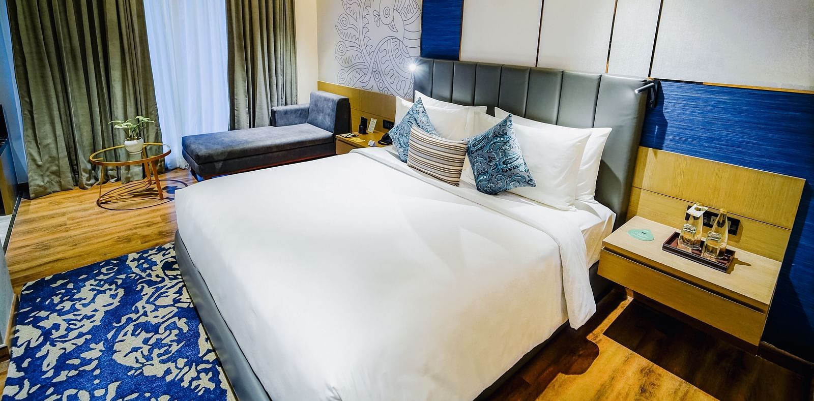 An image of the Deluxe Suite in Madurai with a large bed, a night stand and a couch