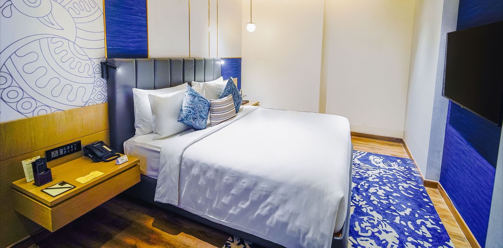 An image of our Junior Suite in Madurai with a night stand placed beside a plush bed