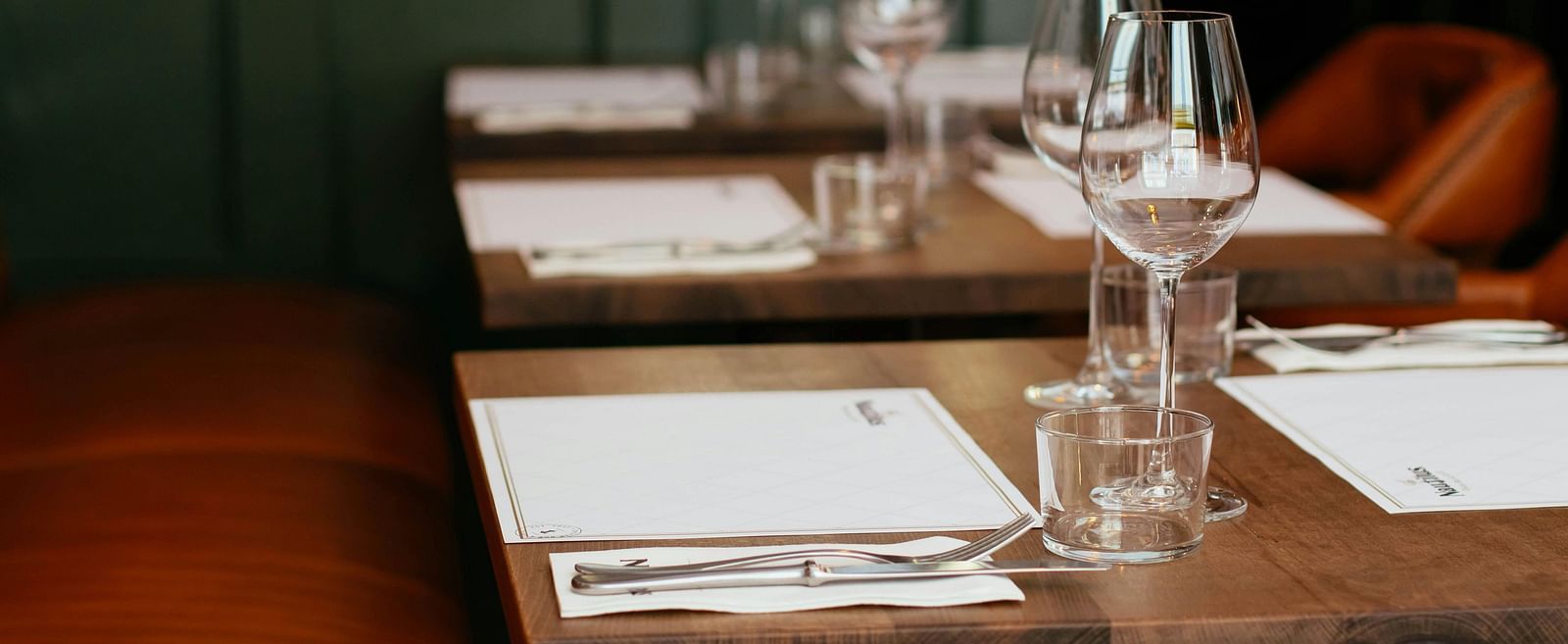A dining setup with clear glasses placed near the menus on a wooden table.