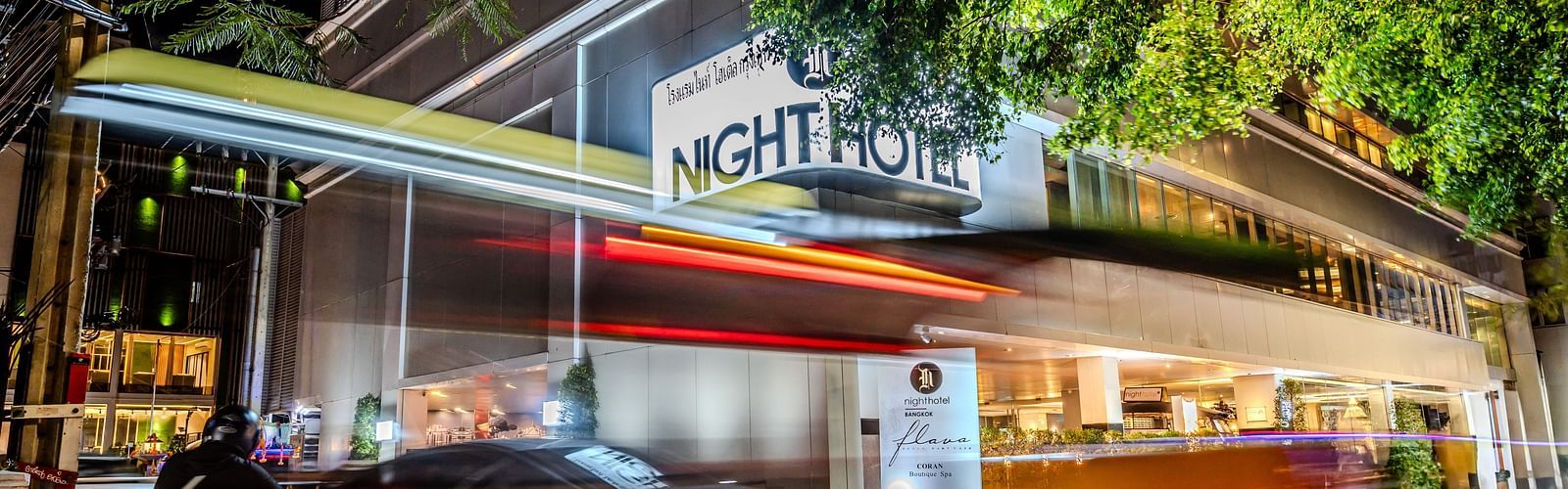A picture showing Night Hotel Bangkok's Facade with vehicles travelling on the road.