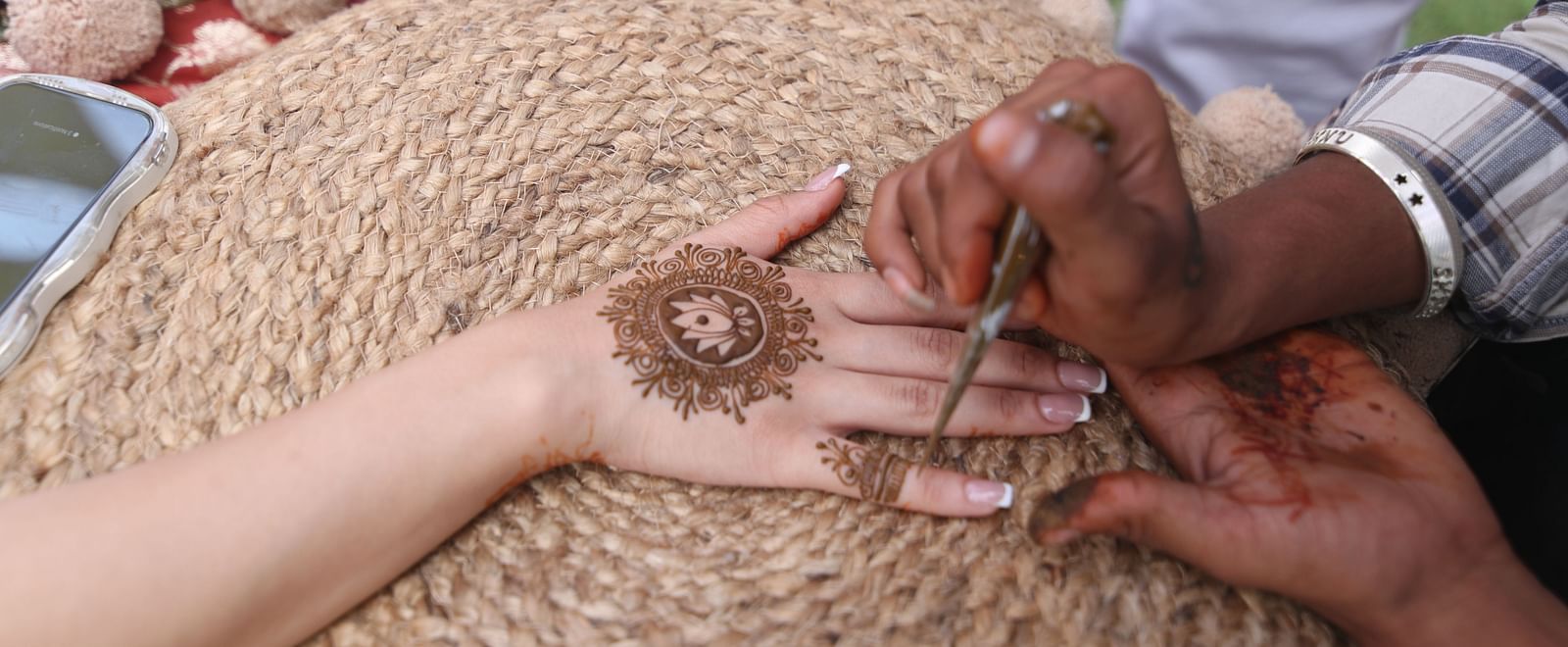 Close-up of applying mehendi on hand during a traditional ceremony at Tisya Farms, Gurgaon.