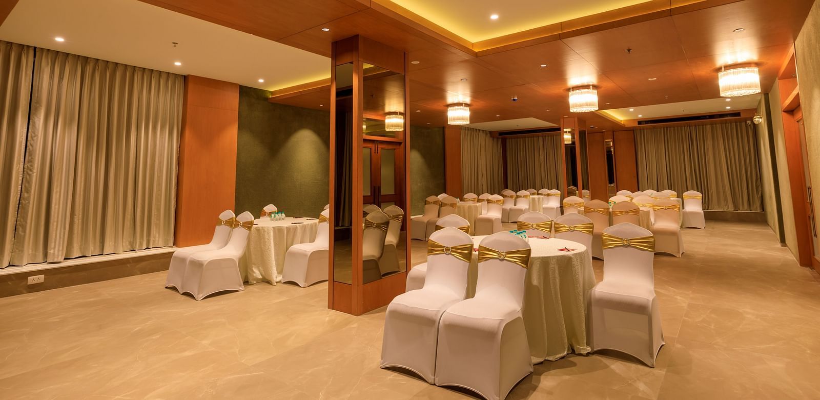 A softly lit function room at Lords Eco Inn Apple Gate is arranged with round tables and covered chairs, ready for an event.