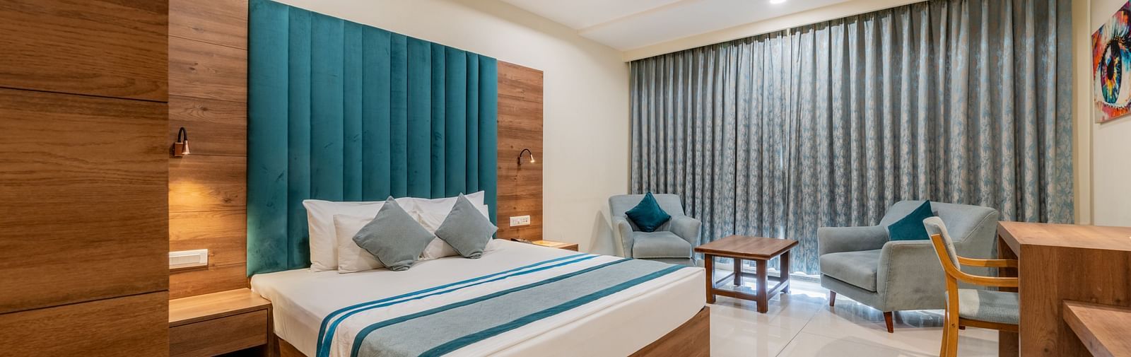 Spacious King size bed room with elegant design, writing desk, and seating area at Hotel Highway King, Bilaspur.