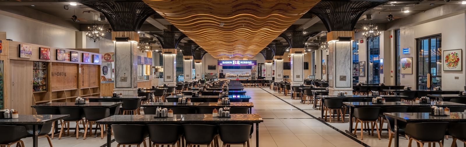 Wide view of dining hall with rows of tables and patterned ceiling at Hotel Highway King, Kishangarh.