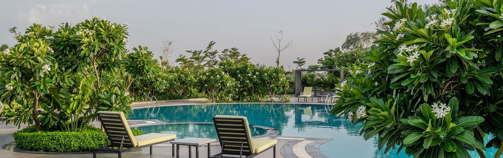 The inviting swimming pool area surrounded by lounge chairs and foliage at Hotel Highway King Shahpura.