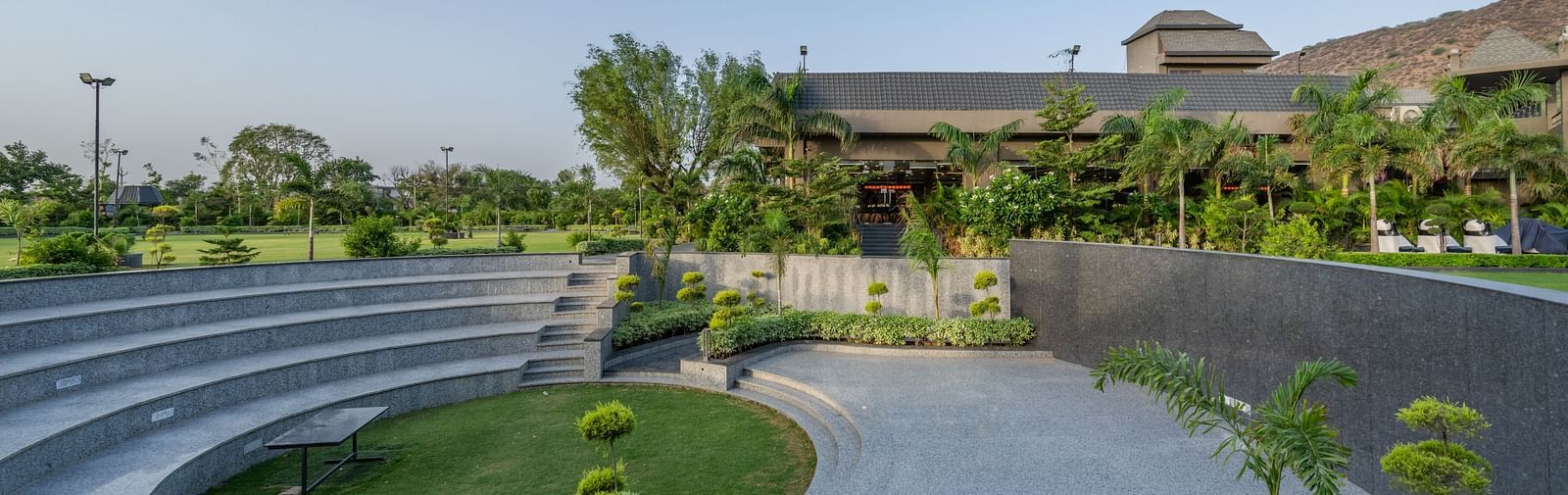 An outdoor amphitheater or tiered seating area with a central green space at Hotel Highway King Shahpura.
