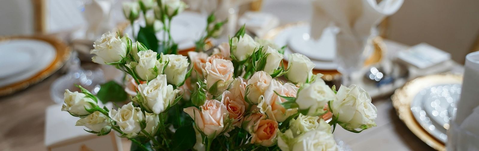 a close up image of a beautiful flower vase with a lot of white and pink roses on a dining table