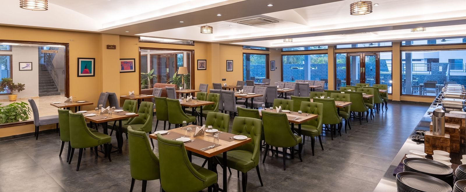 Diagonal view of the restaurant at DLS Forest Vines Resort, featuring tables and seating set for guests.
