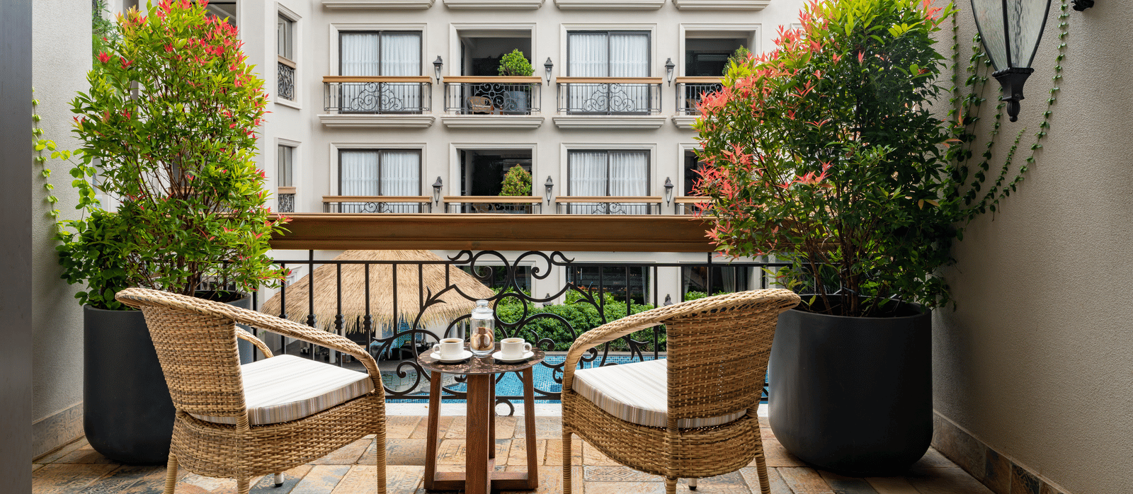 Back shot of the outdoor sit-out area in a balcony of the Premium Room overlooking the swimming pool.