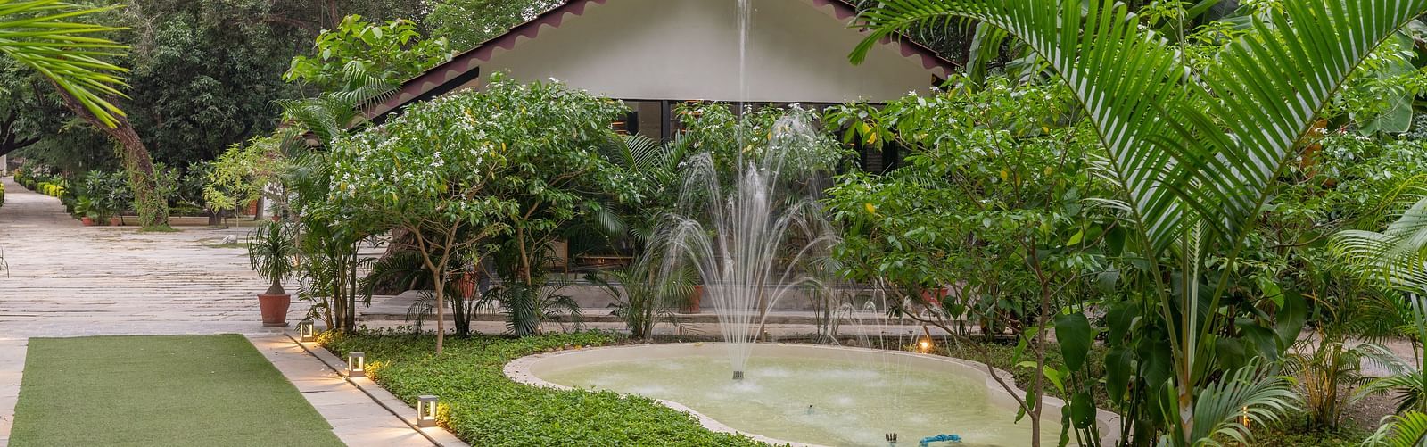 image featuring a pond with a fountain in front of a villa in aranya vilas