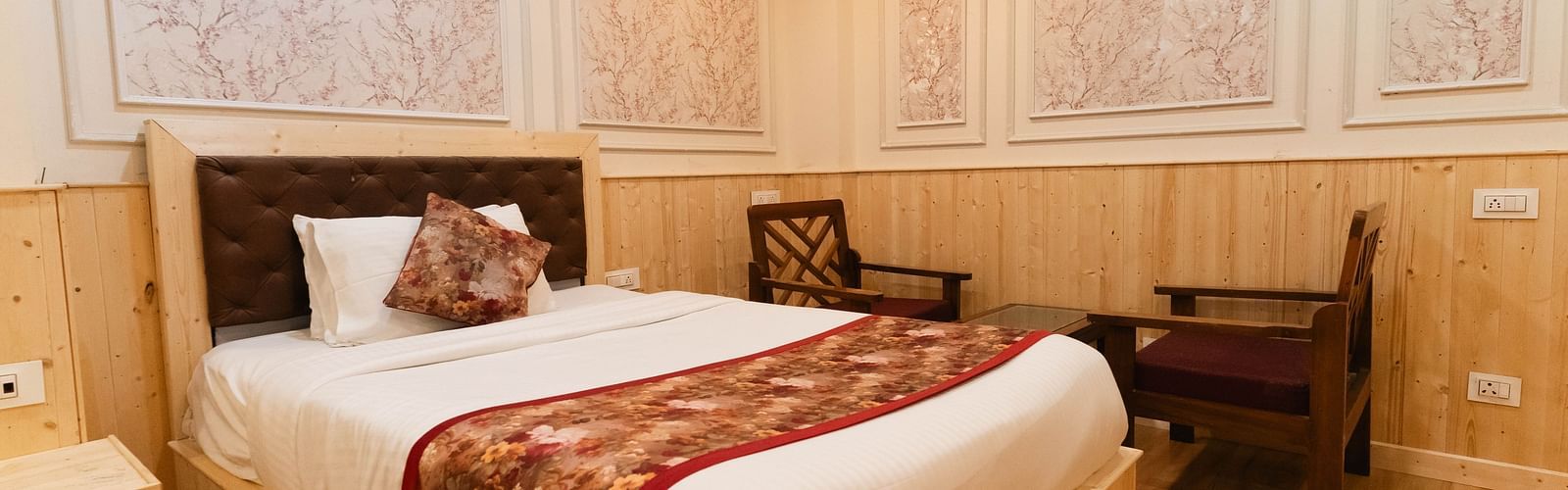 An image of a bedroom with a king size bed and two chair next to it at Avianna New Mandala Hotel & Spa, Darjeeling.