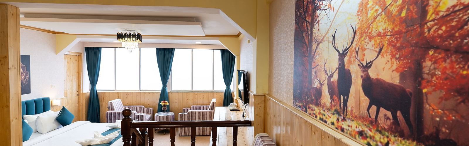 Suite with a king size bed, wall-mounted television, wooden table, and cosy lighting along with attached living room at Avianna Seven Seas, Darjeeling