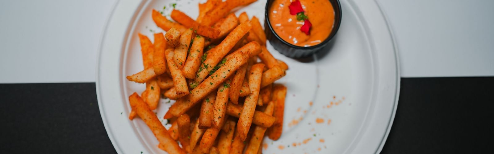 Crispy golden fries served with a spicy dipping sauce, elegantly plated  at D Café, Dip Holidays.