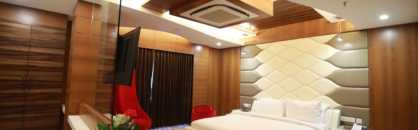 image of a bedroom with a large bed and a red sofa with false ceiling - Hotel Park Elanza, Chennai