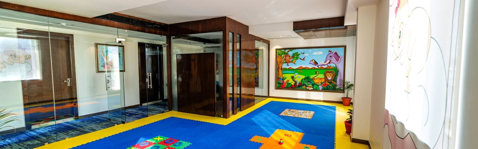 Children's playroom at Inde Reva Resorts Rishhikesh with colourful flooring, soft blocks, indoor lighting, and wall mural.